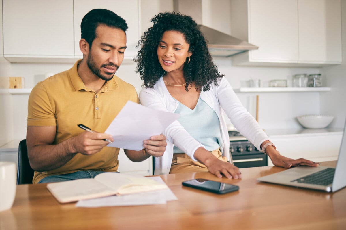 Couple, insurance paperwork and budget planning with laptop