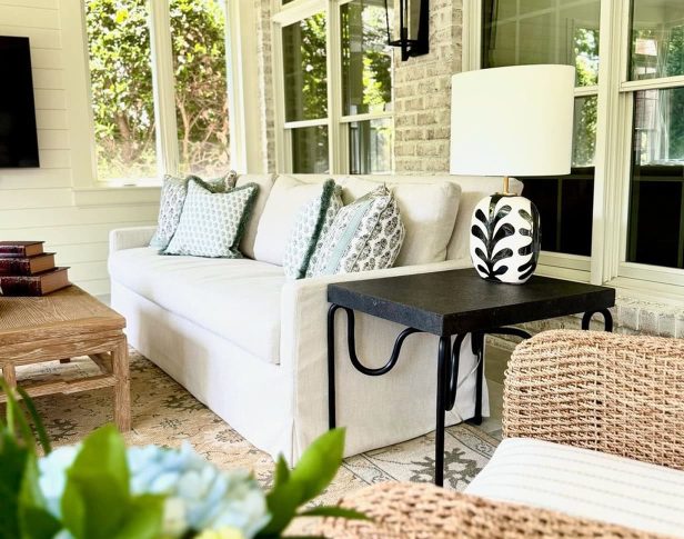 Bright living room interior with a white sofa, patterned pillows, and large windows