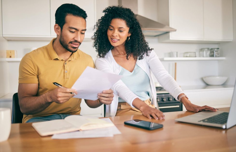 Couple, insurance paperwork and budget planning with laptop